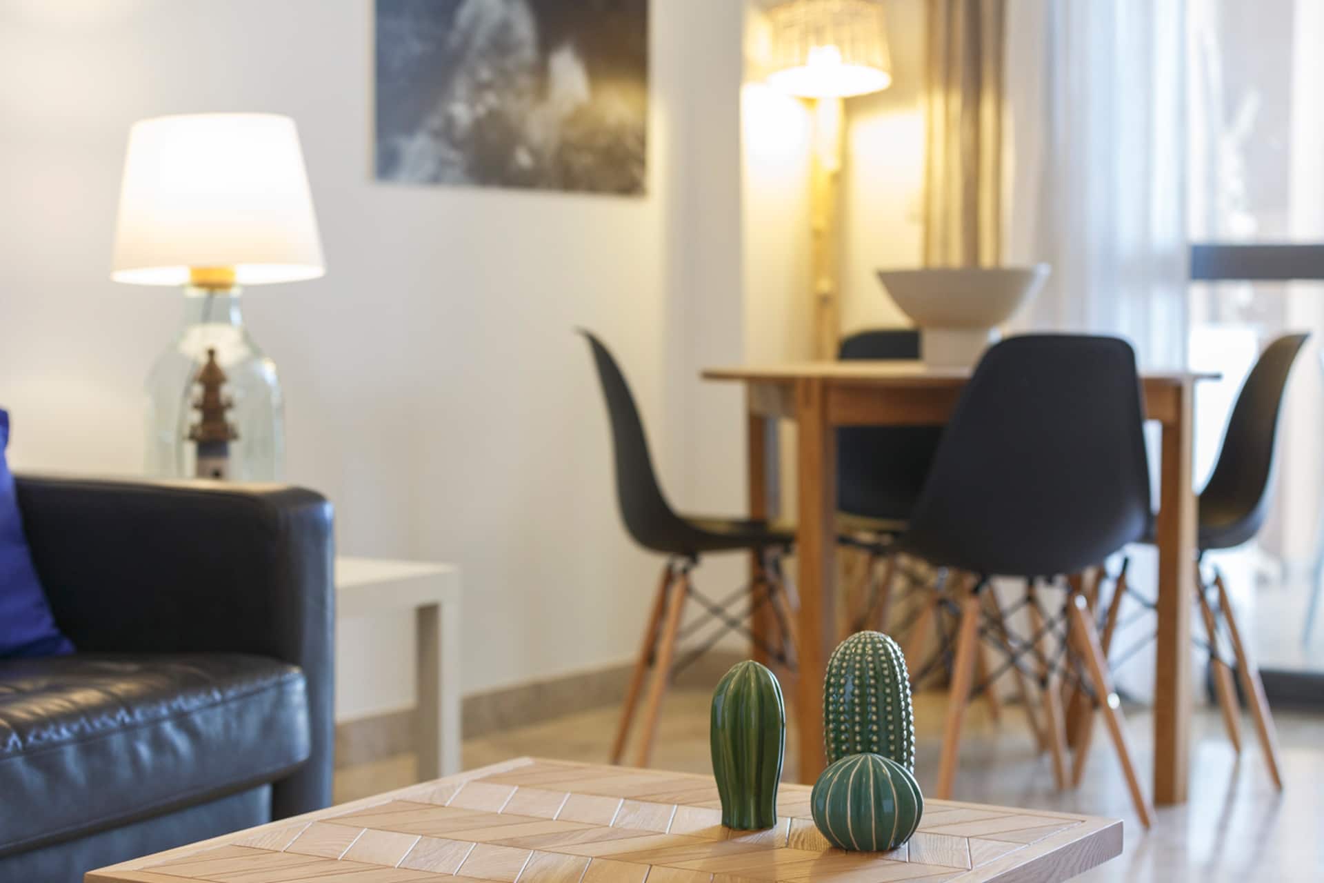Detalle del salón con lámpara de sobremesa y mesa de comedor al fondo.