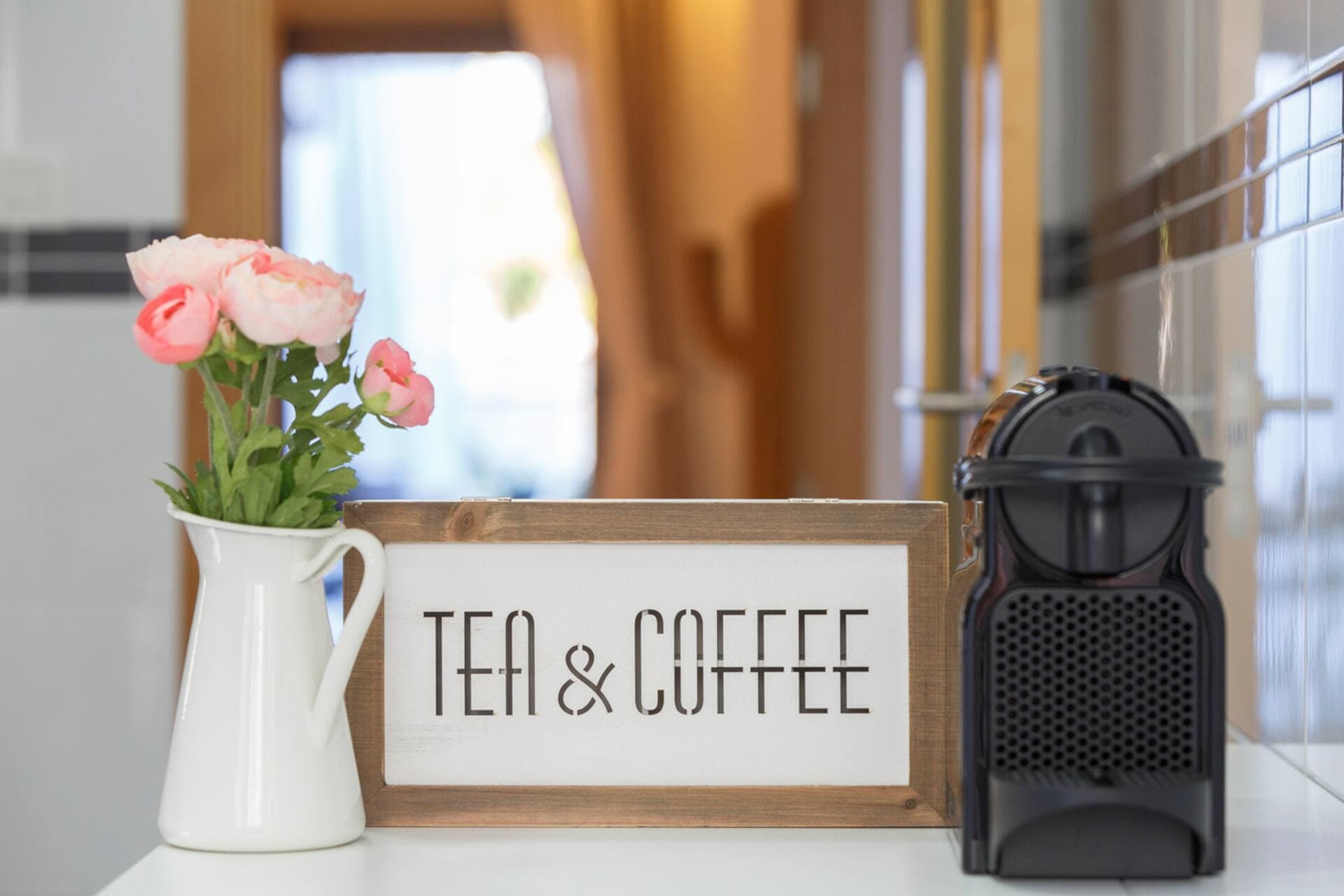 Mesa de desayuno junto a la ventana de la cocina, con cafetera y detalles decorativos.
