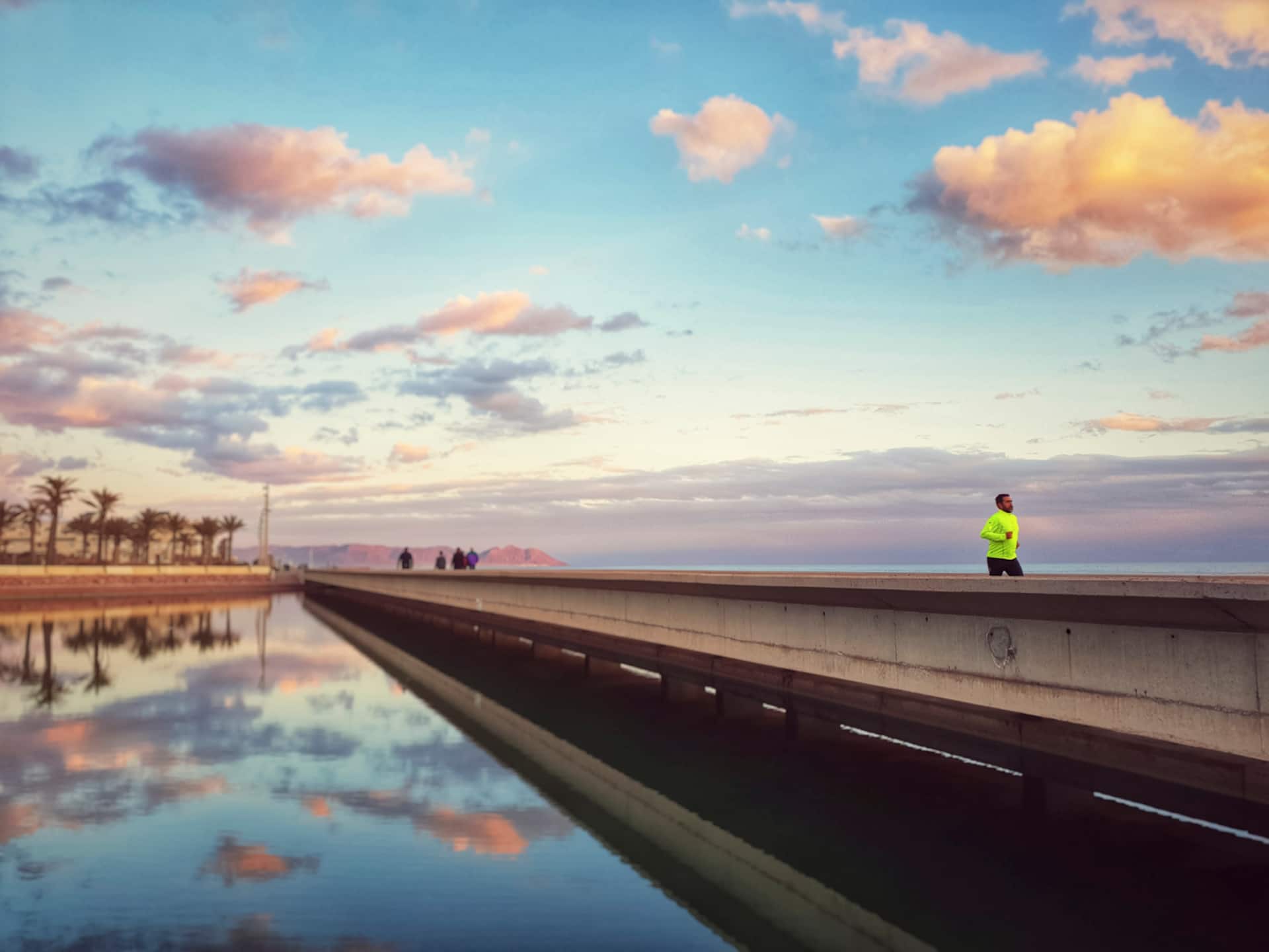 Paseo marítimo de Almería al atardecer, con corredores y palmeras.