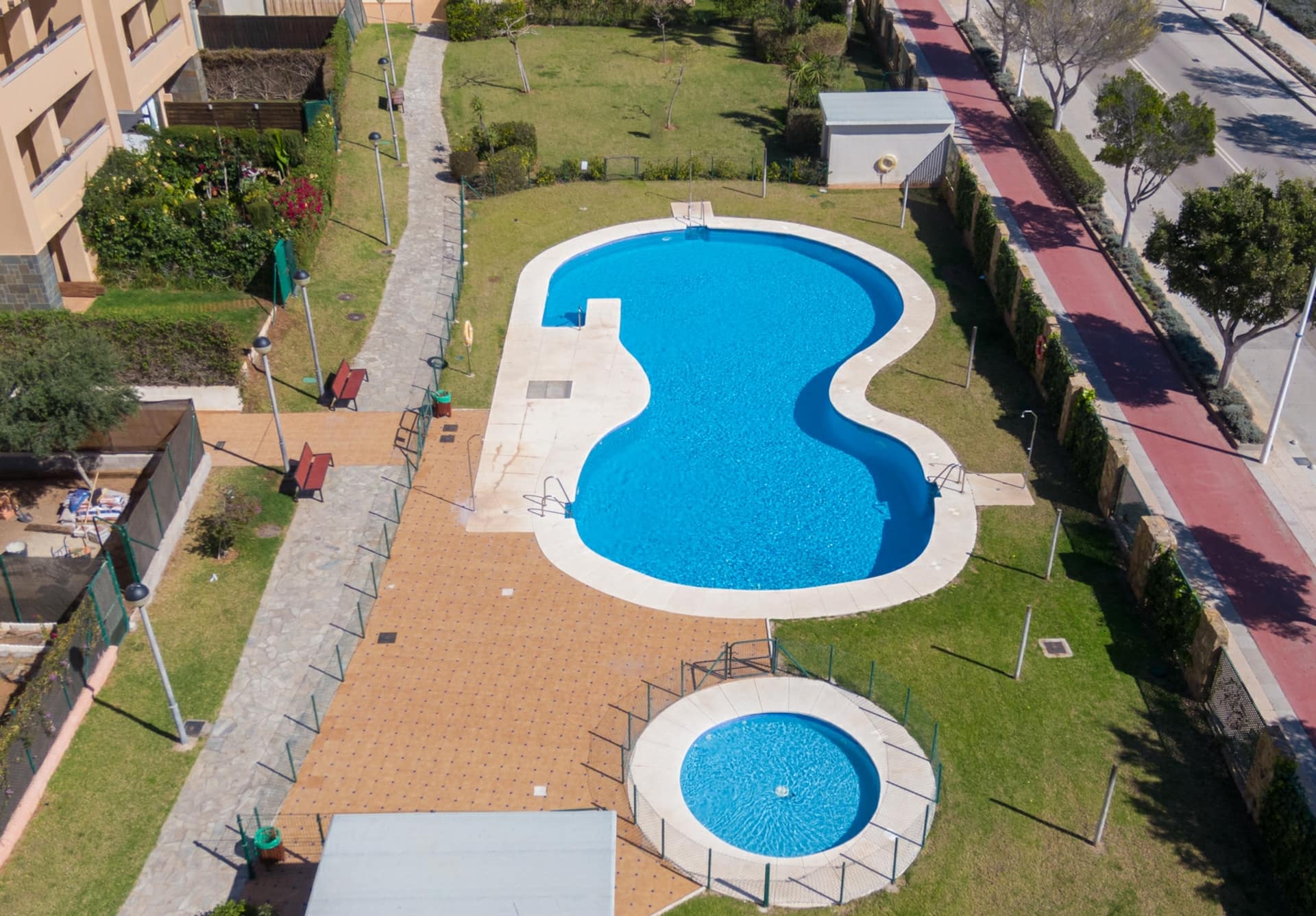 Vista aérea de la piscina comunitaria en forma alargada junto a una zona ajardinada.