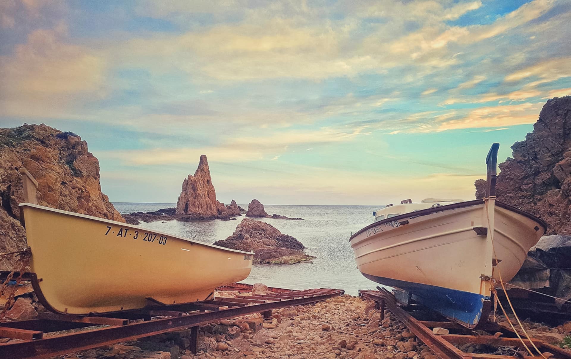 Barcas de pesca varadas junto a una cala rocosa del Cabo de Gata al atardecer.