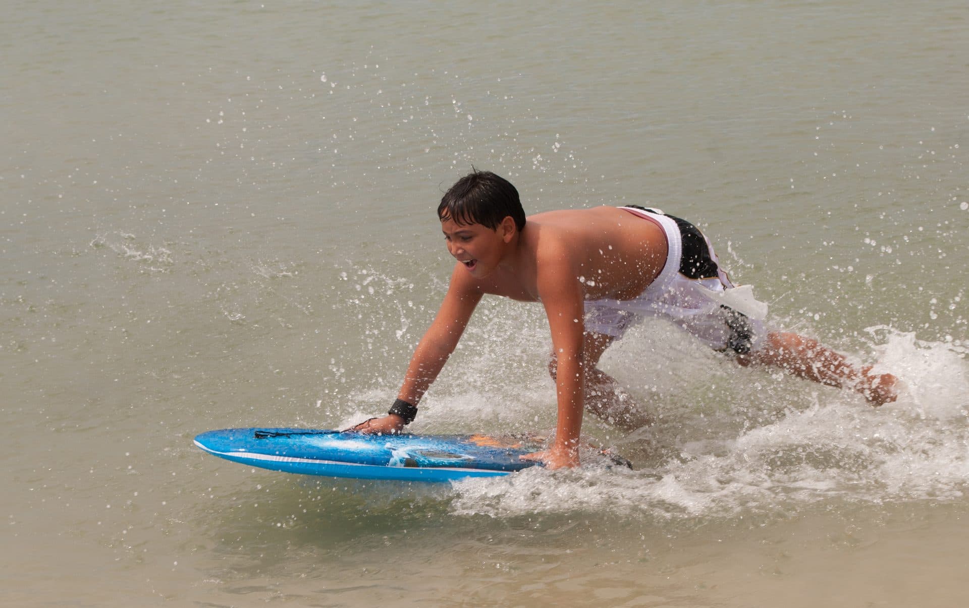 Niño practicando bodyboard en la orilla de la playa.